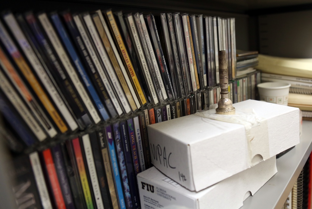 The trumpet mouthpiece of Barry Bernhardt, Flordia International University's Director of Marching Band, sits in front of his music collection. (Photo by Christian Lozano)